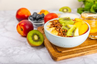 Bir kase granola yoğurt ve dokuma masasında taze böğürtlen. Yoğurt böğürtlen, acai kasesi, spirulina kasesi. Sağlıklı yemek, dengeli kahvaltı. Çilek, yabanmersini, kivi, şeftali, badem ve chia..