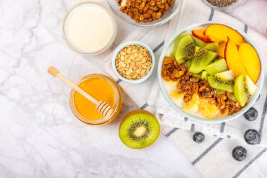 Bir kase granola yoğurt ve dokuma masasında taze böğürtlen. Yoğurt böğürtlen, acai kasesi, spirulina kasesi. Sağlıklı yemek, dengeli kahvaltı. Çilek, yabanmersini, kivi, şeftali, badem ve chia..