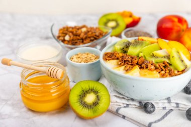 Bir kase granola yoğurt ve dokuma masasında taze böğürtlen. Yoğurt böğürtlen, acai kasesi, spirulina kasesi. Sağlıklı yemek, dengeli kahvaltı. Çilek, yabanmersini, kivi, şeftali, badem ve chia..