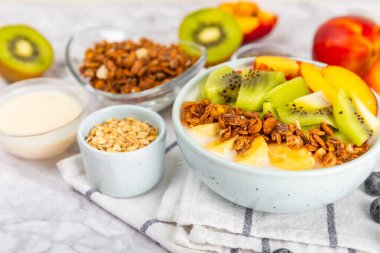 Bir kase granola yoğurt ve dokuma masasında taze böğürtlen. Yoğurt böğürtlen, acai kasesi, spirulina kasesi. Sağlıklı yemek, dengeli kahvaltı. Çilek, yabanmersini, kivi, şeftali, badem ve chia..