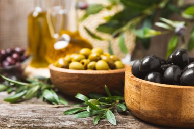 Beyaz ahşap arka planda siyah ve yeşil zeytin seti. Tahta kaselerde çeşitli zeytinler ve taze zeytin yaprakları. Uzayı kopyala Mesaj için yer. Düz lei. Lezzetli.