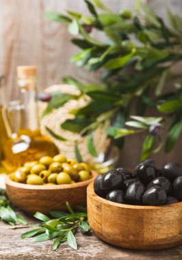 Beyaz ahşap arka planda siyah ve yeşil zeytin seti. Tahta kaselerde çeşitli zeytinler ve taze zeytin yaprakları. Uzayı kopyala Mesaj için yer. Düz lei. Lezzetli.