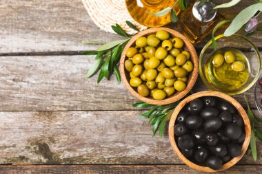 Beyaz ahşap arka planda siyah ve yeşil zeytin seti. Tahta kaselerde çeşitli zeytinler ve taze zeytin yaprakları. Uzayı kopyala Mesaj için yer. Düz lei. Lezzetli.