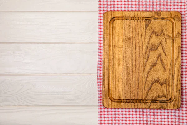 Wooden cutting board on a textured kitchen table. Wooden kitchen board and kitchen towel. Design.MOCKUP. Kitchenware. Place for text. Copy space. Recipe. Cooking concept.