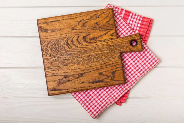 Wooden cutting board on a textured kitchen table. Wooden kitchen board and kitchen towel. Design.MOCKUP. Kitchenware. Place for text. Copy space. Recipe. Cooking concept.