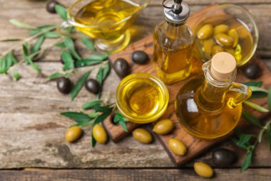Kahverengi desenli bir şişede zeytin yağı. Zeytin dallı ve meyveli yağ şişesi. Mesaj için yer. kopyalama alanı. Yemek yağı ve salata sosu..