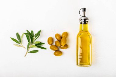 Beyaz dokuya sahip bir şişede zeytin yağı. Zeytin dallı ve meyveli yağ şişesi. Mesaj için yer. kopyalama alanı. Yemek yağı ve salata sosu..