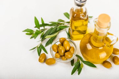Beyaz dokuya sahip bir şişede zeytin yağı. Zeytin dallı ve meyveli yağ şişesi. Mesaj için yer. kopyalama alanı. Yemek yağı ve salata sosu..