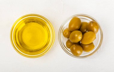 Cam kaselerde zeytinyağı, soslu kayıklar ve dokulu mutfak masasında şişe. Zeytin dallı ve meyveli yağ şişesi. Mesaj için yer. kopyalama alanı. Yemek yağı ve salata sosu. Yakın plan.