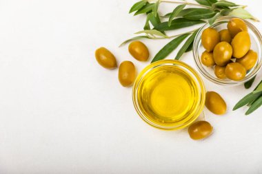 Cam kaselerde zeytinyağı, soslu kayıklar ve dokulu mutfak masasında şişe. Zeytin dallı ve meyveli yağ şişesi. Mesaj için yer. kopyalama alanı. Yemek yağı ve salata sosu. Yakın plan.