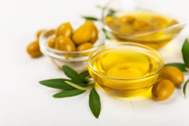 Cam kaselerde zeytinyağı, soslu kayıklar ve dokulu mutfak masasında şişe. Zeytin dallı ve meyveli yağ şişesi. Mesaj için yer. kopyalama alanı. Yemek yağı ve salata sosu. Yakın plan.