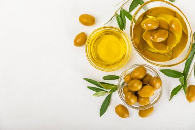 Cam kaselerde zeytinyağı, soslu kayıklar ve dokulu mutfak masasında şişe. Zeytin dallı ve meyveli yağ şişesi. Mesaj için yer. kopyalama alanı. Yemek yağı ve salata sosu. Yakın plan.