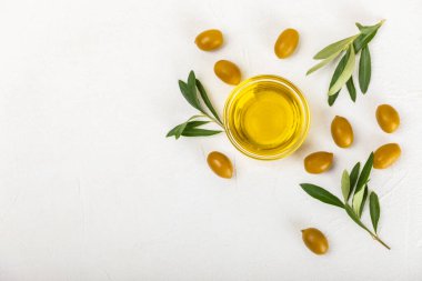 Cam kaselerde zeytinyağı, soslu kayıklar ve dokulu mutfak masasında şişe. Zeytin dallı ve meyveli yağ şişesi. Mesaj için yer. kopyalama alanı. Yemek yağı ve salata sosu. Yakın plan.