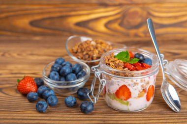 Granola kasesi. Yulaf ezmeli yoğurt, taze böğürtlen, spirulina ve chia çekirdeği. Sağlıklı yiyecekler. Lezzetli bir kahvaltı. Çilekli yoğurt, ahududu, yabanmersini, şeftali, nane ve mendal. Boşluğu kopyala.