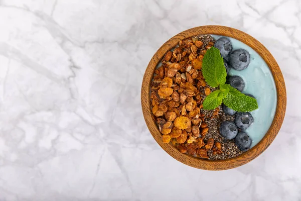 Granola bowl. Yogurt with oatmeal, fresh berries, spirulina and chia seeds. Healthly food. Tasty breakfast. Yogurt with strawberries, raspberries, blueberries, peaches, mint and mendal. Copy space.