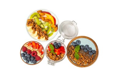 Beyaz arka planda taze böğürtlenli granola kasesi, spirulina ve chia tohumları var. Sağlıklı yiyecekler. Lezzetli bir kahvaltı. Çilekli yoğurt, ahududu, yabanmersini, şeftali, nane ve mendal.