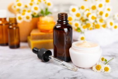 Papatya spası. Papatya çiçekleri, el yapımı sabun, temel yağ kozmetik şişesi, vücut kremi, ovalama ve beyaz desenli deniz tuzu karışımı. Rahatlatıcı güzellik tedavileri. Boşluğu kopyala