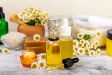 Papatya spası. Papatya çiçekleri, el yapımı sabun, temel yağ kozmetik şişesi, vücut kremi, ovalama ve beyaz desenli deniz tuzu karışımı. Rahatlatıcı güzellik tedavileri. Boşluğu kopyala