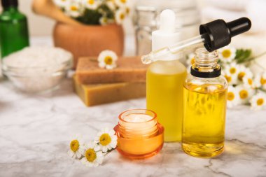 Papatya spası. Papatya çiçekleri, el yapımı sabun, temel yağ kozmetik şişesi, vücut kremi, ovalama ve beyaz desenli deniz tuzu karışımı. Rahatlatıcı güzellik tedavileri. Boşluğu kopyala