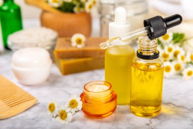 Papatya spası. Papatya çiçekleri, el yapımı sabun, temel yağ kozmetik şişesi, vücut kremi, ovalama ve beyaz desenli deniz tuzu karışımı. Rahatlatıcı güzellik tedavileri. Boşluğu kopyala