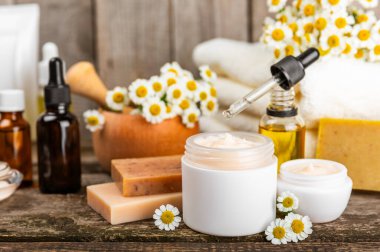 Papatya spası. Papatya çiçekleri, el yapımı sabun, temel yağ kozmetik şişesi, vücut kremi, ovalama ve beyaz desenli deniz tuzu karışımı. Rahatlatıcı güzellik tedavileri. Boşluğu kopyala