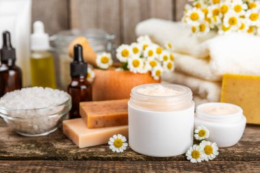 Papatya spası. Papatya çiçekleri, el yapımı sabun, temel yağ kozmetik şişesi, vücut kremi, ovalama ve beyaz desenli deniz tuzu karışımı. Rahatlatıcı güzellik tedavileri. Boşluğu kopyala