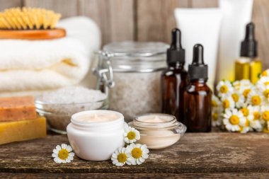Papatya spası. Papatya çiçekleri, el yapımı sabun, temel yağ kozmetik şişesi, vücut kremi, ovalama ve beyaz desenli deniz tuzu karışımı. Rahatlatıcı güzellik tedavileri. Boşluğu kopyala