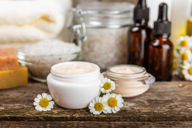 Papatya spası. Papatya çiçekleri, el yapımı sabun, temel yağ kozmetik şişesi, vücut kremi, ovalama ve beyaz desenli deniz tuzu karışımı. Rahatlatıcı güzellik tedavileri. Boşluğu kopyala