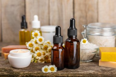 Papatya spası. Papatya çiçekleri, el yapımı sabun, temel yağ kozmetik şişesi, vücut kremi, ovalama ve beyaz desenli deniz tuzu karışımı. Rahatlatıcı güzellik tedavileri. Boşluğu kopyala