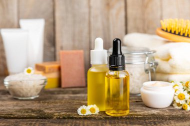 Papatya spası. Papatya çiçekleri, el yapımı sabun, temel yağ kozmetik şişesi, vücut kremi, ovalama ve beyaz desenli deniz tuzu karışımı. Rahatlatıcı güzellik tedavileri. Boşluğu kopyala