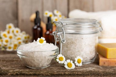 Papatya spası. Papatya çiçekleri, el yapımı sabun, temel yağ kozmetik şişesi, vücut kremi, ovalama ve beyaz desenli deniz tuzu karışımı. Rahatlatıcı güzellik tedavileri. Boşluğu kopyala