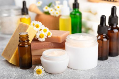 Papatya spası. Papatya çiçekleri, el yapımı sabun, temel yağ kozmetik şişesi, vücut kremi, ovalama ve beyaz desenli deniz tuzu karışımı. Rahatlatıcı güzellik tedavileri. Boşluğu kopyala