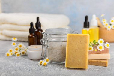 Papatya spası. Papatya çiçekleri, el yapımı sabun, temel yağ kozmetik şişesi, vücut kremi, ovalama ve beyaz desenli deniz tuzu karışımı. Rahatlatıcı güzellik tedavileri. Boşluğu kopyala