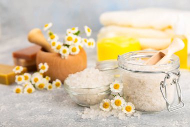 Papatya spası. Papatya çiçekleri, el yapımı sabun, temel yağ kozmetik şişesi, vücut kremi, ovalama ve beyaz desenli deniz tuzu karışımı. Rahatlatıcı güzellik tedavileri. Boşluğu kopyala