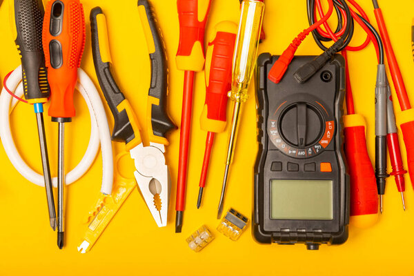 Electrician tools on background.Multimeter,construction tape,electrical tape, screwdrivers,pliers,an automatic insulation stripper, socket and LED lamp.Flatley.electrician concept.