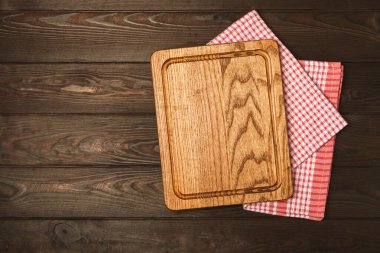 Ahşap mutfak masasında havlunun üzerinde tahta kesme tahtası. Çimento arka planında kesme tahtası ve mutfak havlusu. Menü yemek kartı ya da yemek tarifleri arka plan kavramı. MOCKUP Tasarım. Metin için yer, kopyalama alanı.