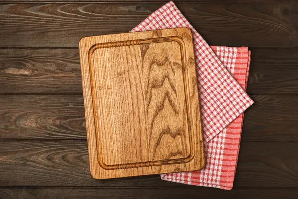 Cutting board over towel on wooden kitchen table. Cutting board and kitchen towel on a cement background. Menu food card or recipes background concept.MOCKUP. Design. Place for text, copy space.