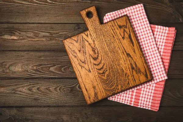 Cutting board over towel on wooden kitchen table. Cutting board and kitchen towel on a cement background. Menu food card or recipes background concept.MOCKUP. Design. Place for text, copy space.