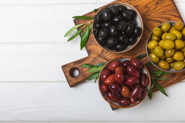 Dokulu arka planda yeşil ve siyah zeytin. Farklı türde zeytin ve taze zeytin yapraklı zeytin yağları. Lezzetli. Akdeniz mutfağı. Boşluğu kopyala.