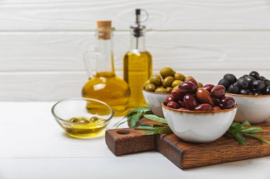 Dokulu arka planda yeşil ve siyah zeytin. Farklı türde zeytin ve taze zeytin yapraklı zeytin yağları. Lezzetli. Akdeniz mutfağı. Boşluğu kopyala.