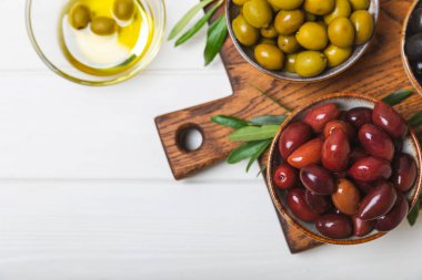 Dokulu arka planda yeşil ve siyah zeytin. Farklı türde zeytin ve taze zeytin yapraklı zeytin yağları. Lezzetli. Akdeniz mutfağı. Boşluğu kopyala.