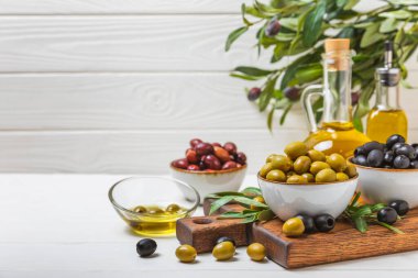 Dokulu arka planda yeşil ve siyah zeytin. Farklı türde zeytin ve taze zeytin yapraklı zeytin yağları. Lezzetli. Akdeniz mutfağı. Boşluğu kopyala.