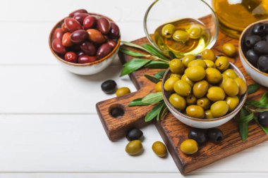 Dokulu arka planda yeşil ve siyah zeytin. Farklı türde zeytin ve taze zeytin yapraklı zeytin yağları. Lezzetli. Akdeniz mutfağı. Boşluğu kopyala.