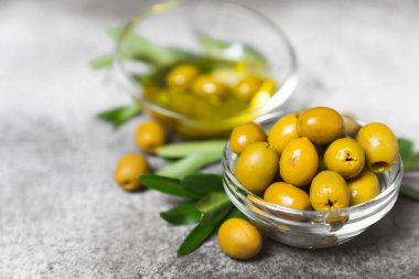 Dokulu arka planda yeşil ve siyah zeytin. Farklı türde zeytin ve taze zeytin yapraklı zeytin yağları. Lezzetli. Akdeniz mutfağı. Boşluğu kopyala.