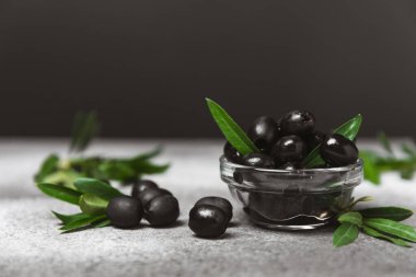 Dokulu arka planda yeşil ve siyah zeytin. Farklı türde zeytin ve taze zeytin yapraklı zeytin yağları. Lezzetli. Akdeniz mutfağı. Boşluğu kopyala.