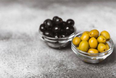 Dokulu arka planda yeşil ve siyah zeytin. Farklı türde zeytin ve taze zeytin yapraklı zeytin yağları. Lezzetli. Akdeniz mutfağı. Boşluğu kopyala.