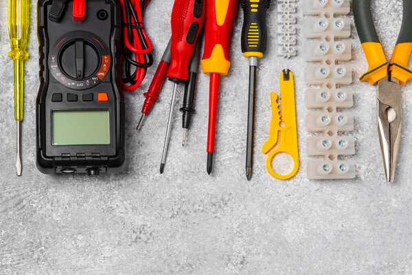 Electrician tools on background.Multimeter,construction tape,electrical tape, screwdrivers,pliers,an automatic insulation stripper, socket and LED lamp.Flatley.electrician concept.