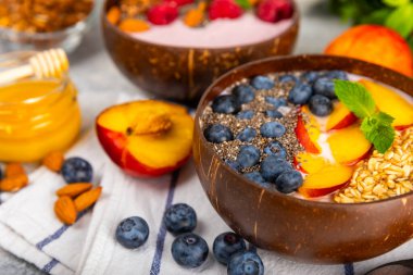 Bir kase granola yoğurt ve dokuma masasında taze böğürtlen. Yoğurt böğürtlen, acai kasesi, spirulina kasesi. Sağlıklı yemek, dengeli kahvaltı. Çilek, yabanmersini, kivi, şeftali, badem ve chia..