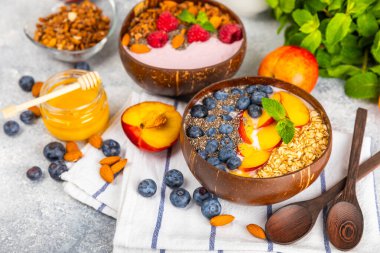 Bir kase granola yoğurt ve dokuma masasında taze böğürtlen. Yoğurt böğürtlen, acai kasesi, spirulina kasesi. Sağlıklı yemek, dengeli kahvaltı. Çilek, yabanmersini, kivi, şeftali, badem ve chia..