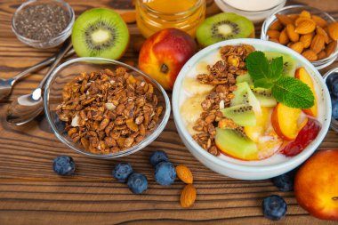 Bir kase granola yoğurt ve dokuma masasında taze böğürtlen. Yoğurt böğürtlen, acai kasesi, spirulina kasesi. Sağlıklı yemek, dengeli kahvaltı. Çilek, yabanmersini, kivi, şeftali, badem ve chia..